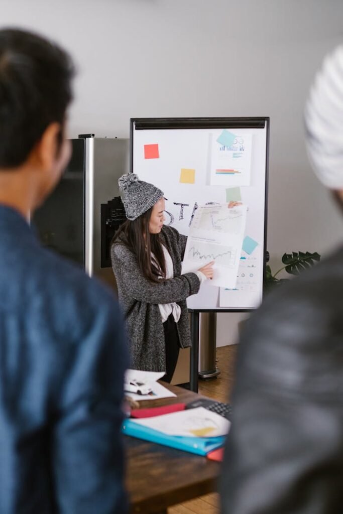 A young woman presenting business plans to a team in a modern office setting.